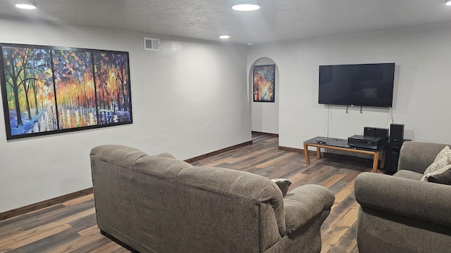 living room with a textured ceiling and dark hardwood / wood-style floors