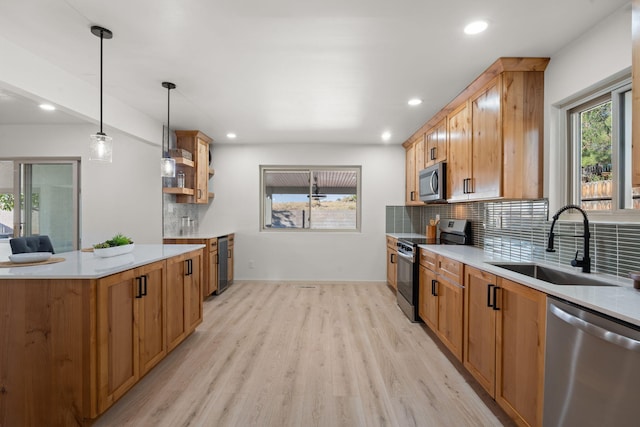 kitchen with sink, decorative backsplash, hanging light fixtures, stainless steel appliances, and light hardwood / wood-style flooring