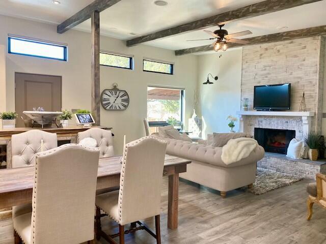 living room featuring ceiling fan, a fireplace, beamed ceiling, and hardwood / wood-style floors