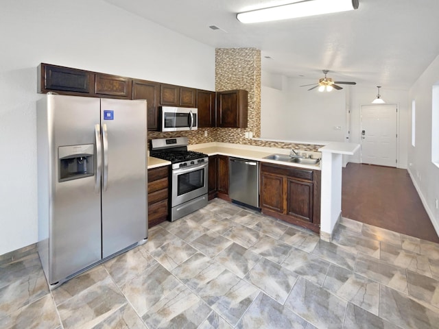 kitchen with ceiling fan, decorative backsplash, kitchen peninsula, sink, and stainless steel appliances