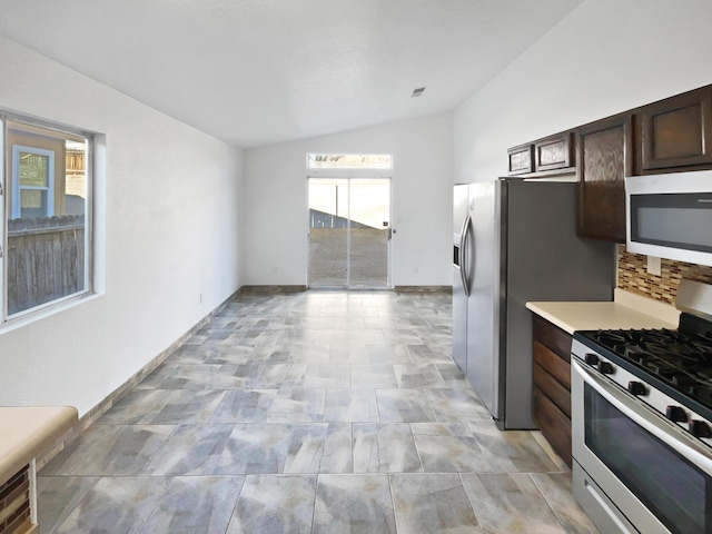 kitchen featuring vaulted ceiling, appliances with stainless steel finishes, decorative backsplash, and dark brown cabinetry