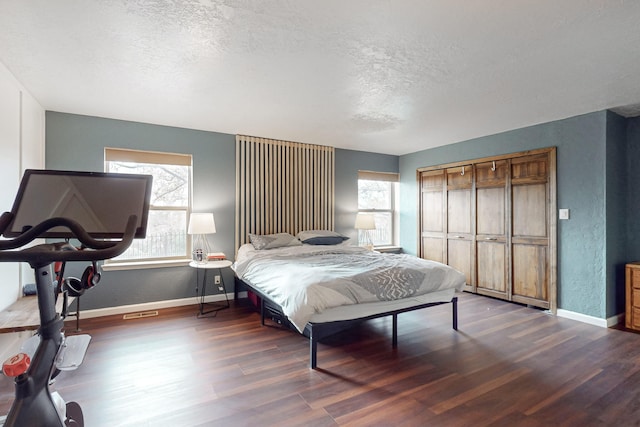 bedroom with dark wood-type flooring, a closet, and a textured ceiling