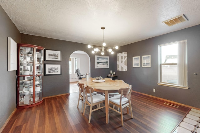 dining space with a notable chandelier, dark hardwood / wood-style floors, and a textured ceiling