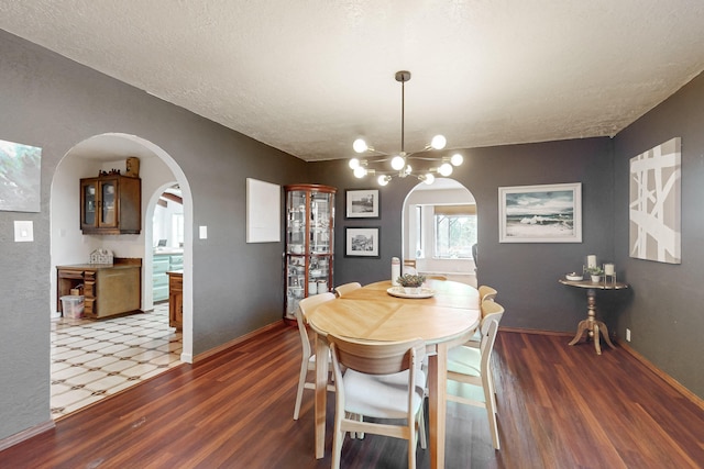 dining area featuring a notable chandelier, dark wood-type flooring, and a textured ceiling