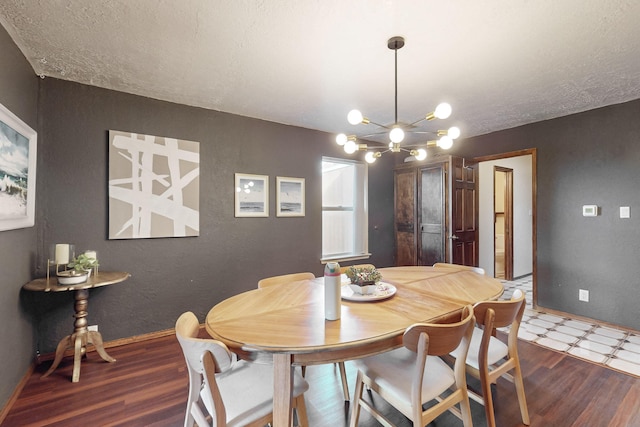 dining space featuring dark hardwood / wood-style flooring, a notable chandelier, and a textured ceiling