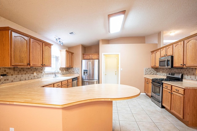 kitchen featuring lofted ceiling, sink, light tile patterned floors, kitchen peninsula, and stainless steel appliances