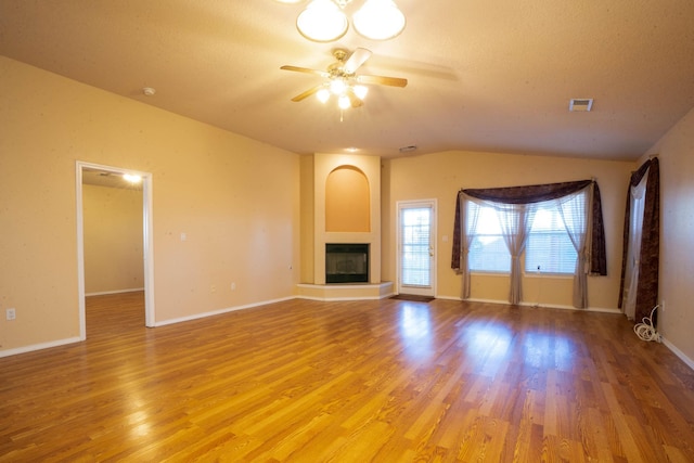 unfurnished living room featuring lofted ceiling, a fireplace, ceiling fan, and light wood-type flooring