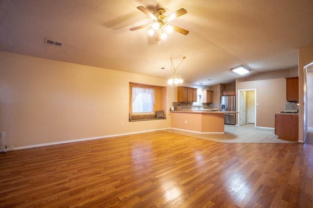 interior space featuring lofted ceiling, kitchen peninsula, stainless steel fridge with ice dispenser, and decorative backsplash