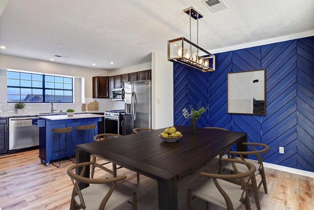 dining area featuring sink, a textured ceiling, and light hardwood / wood-style flooring