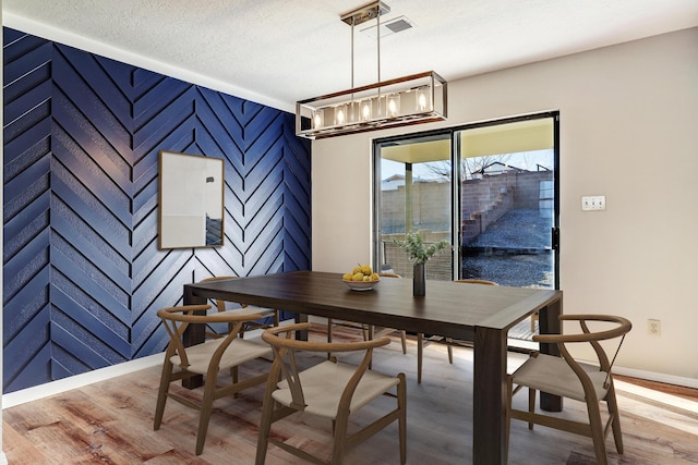 dining room with a notable chandelier, a textured ceiling, and hardwood / wood-style flooring