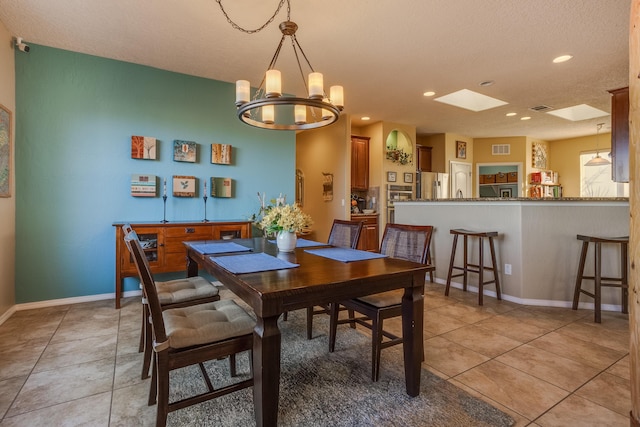 dining area featuring a textured ceiling, an inviting chandelier, and light tile patterned flooring