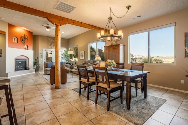 dining room featuring ceiling fan with notable chandelier, a textured ceiling, light tile patterned floors, and beamed ceiling