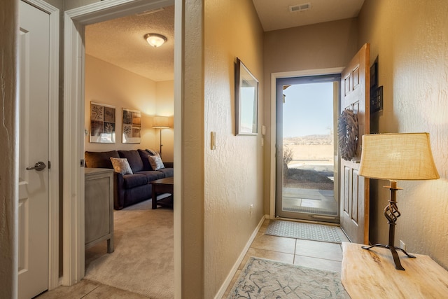 entryway with a textured ceiling and light tile patterned floors