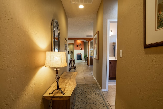 hallway with a textured ceiling and light tile patterned flooring