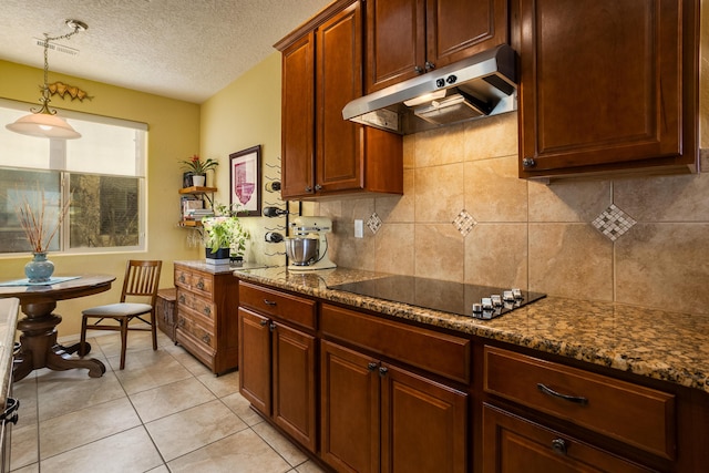 kitchen with light tile patterned floors, black electric stovetop, dark stone countertops, a textured ceiling, and pendant lighting