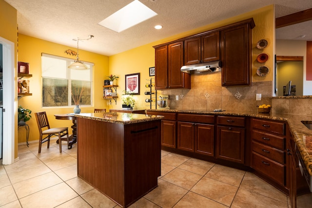 kitchen with a textured ceiling, a skylight, light tile patterned flooring, and hanging light fixtures