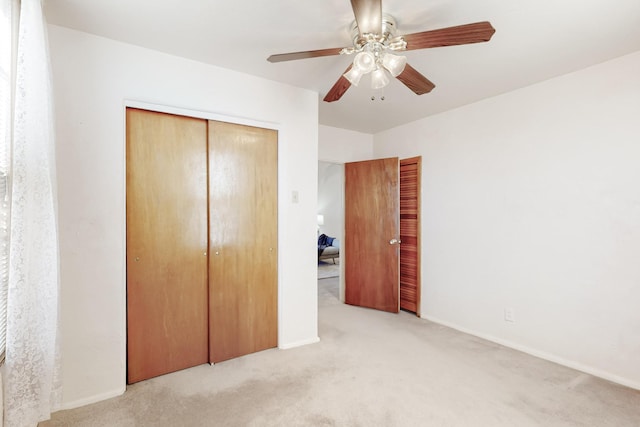 unfurnished bedroom with ceiling fan, light colored carpet, and a closet