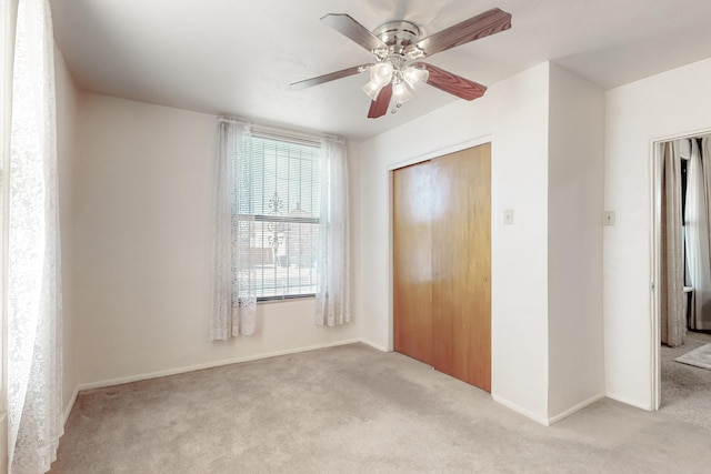 unfurnished bedroom with ceiling fan, light colored carpet, and a closet