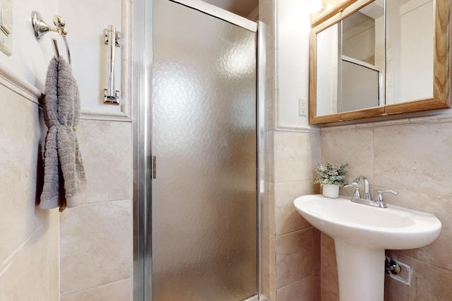 bathroom featuring tile walls and a shower with shower door