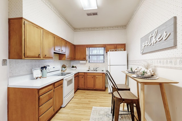 kitchen featuring sink, light hardwood / wood-style floors, and white appliances