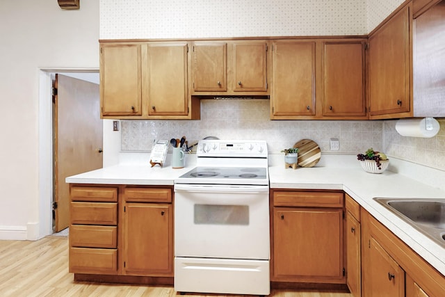 kitchen with white range with electric cooktop, decorative backsplash, sink, and light hardwood / wood-style flooring