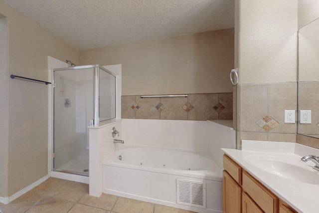 bathroom with a textured ceiling, tile patterned floors, vanity, and plus walk in shower