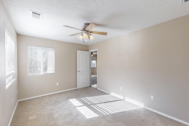 spare room with ceiling fan, light colored carpet, and a textured ceiling