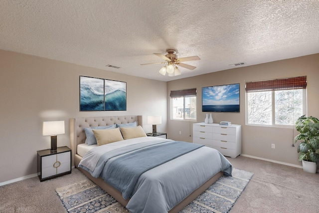 bedroom with ceiling fan, light colored carpet, and a textured ceiling