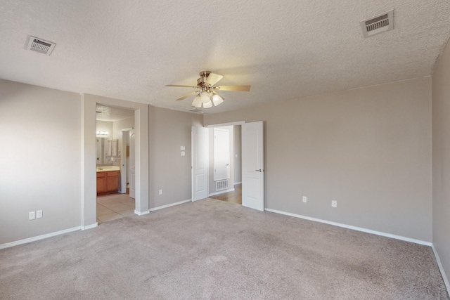 spare room featuring ceiling fan, a textured ceiling, and light carpet