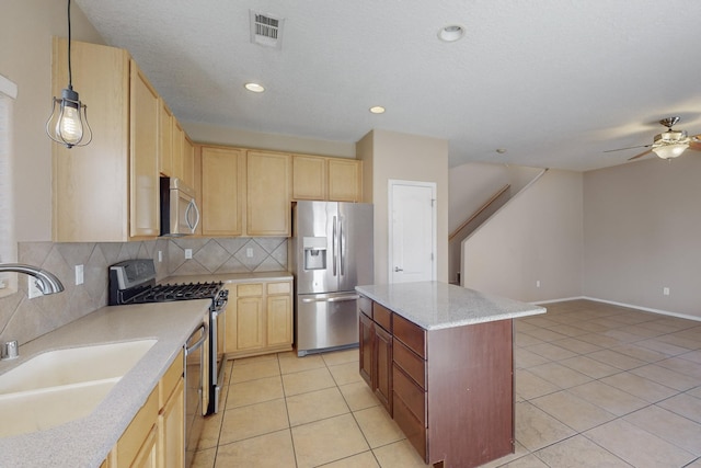 kitchen with a center island, decorative light fixtures, stainless steel appliances, sink, and light tile patterned floors