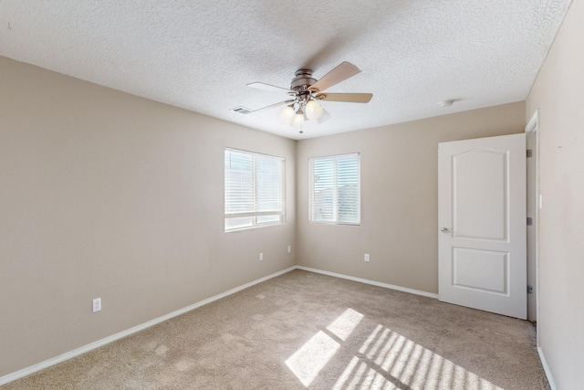 carpeted spare room featuring ceiling fan and a textured ceiling