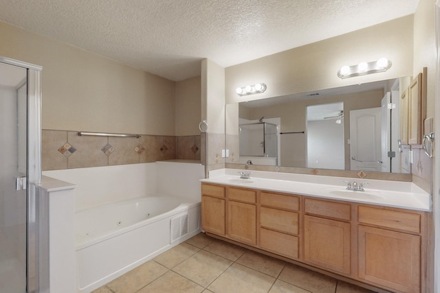 bathroom with a textured ceiling, vanity, independent shower and bath, and tile patterned flooring