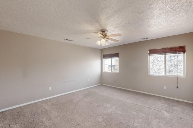 empty room with ceiling fan, a textured ceiling, and light carpet