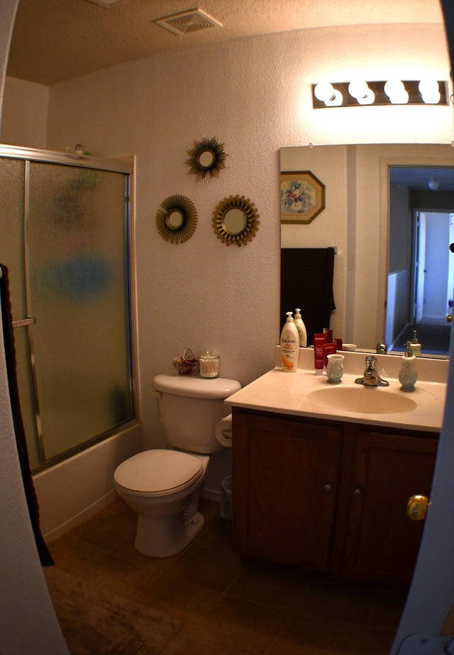 bathroom featuring toilet, vanity, visible vents, and enclosed tub / shower combo