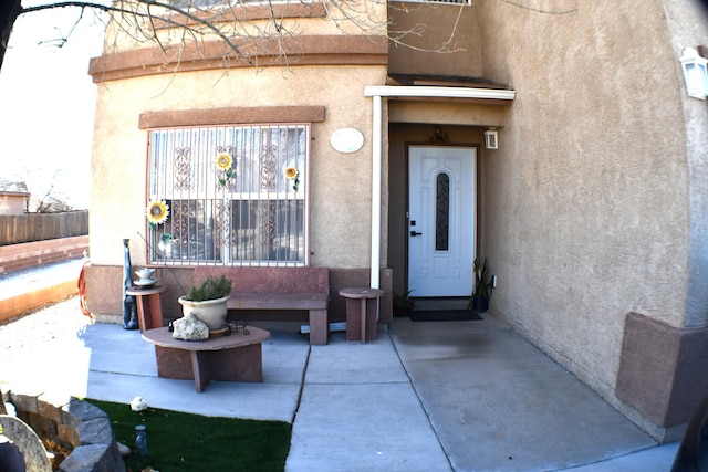 property entrance featuring fence and stucco siding