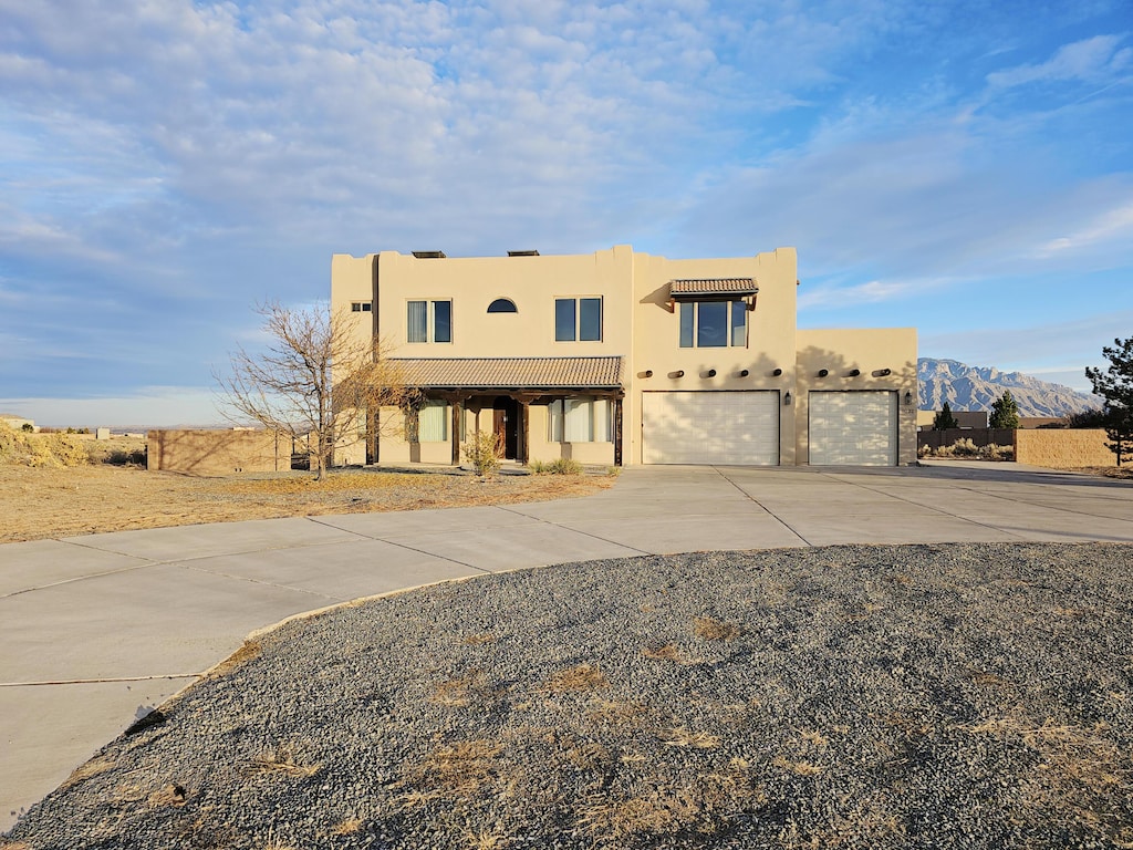 pueblo-style home with a garage and a mountain view