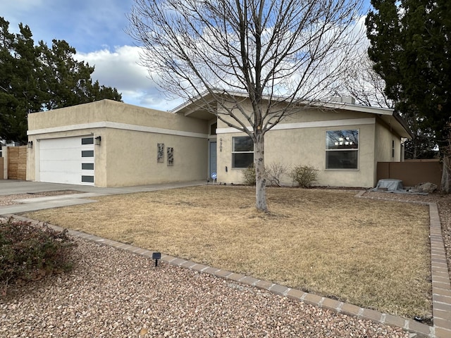 view of front of property featuring stucco siding, concrete driveway, an attached garage, and fence