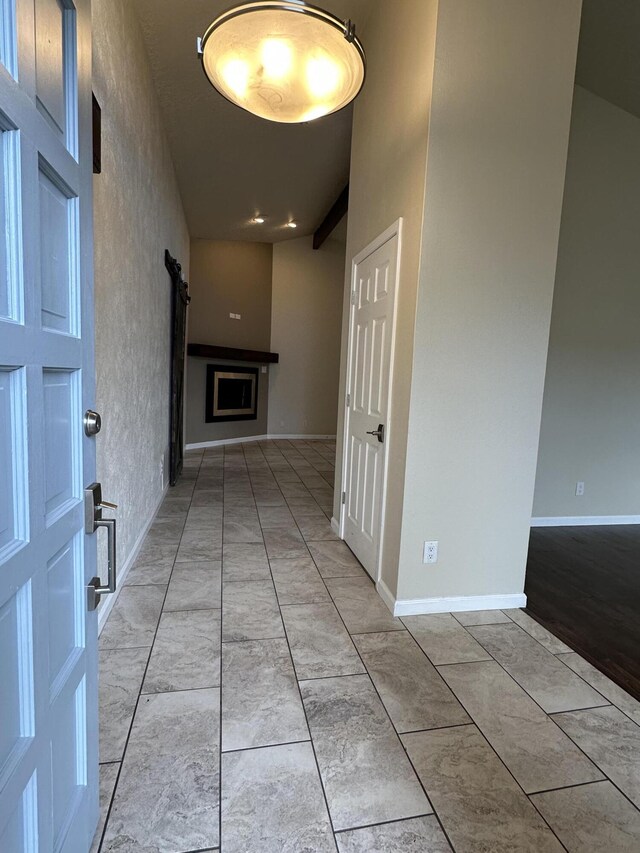 corridor featuring a barn door and baseboards