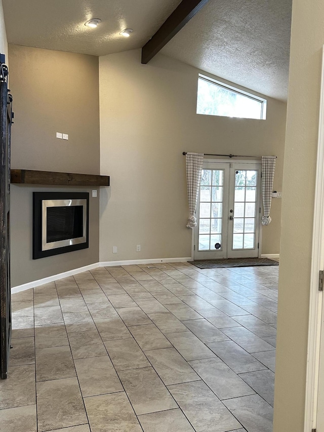 unfurnished living room featuring tile patterned flooring, beamed ceiling, a textured ceiling, and baseboards