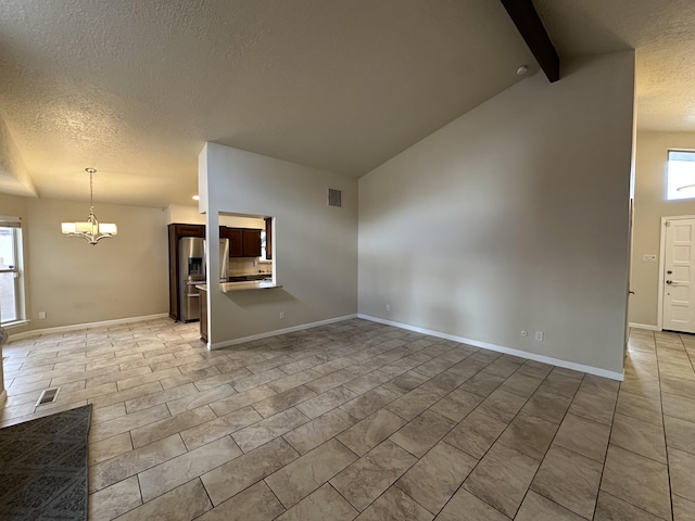 unfurnished living room with baseboards, visible vents, a textured ceiling, beamed ceiling, and a chandelier