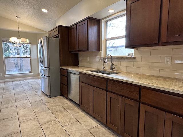 kitchen featuring tasteful backsplash, a chandelier, lofted ceiling, appliances with stainless steel finishes, and a sink