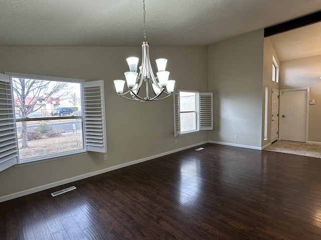 unfurnished dining area with visible vents, a textured ceiling, wood finished floors, an inviting chandelier, and baseboards