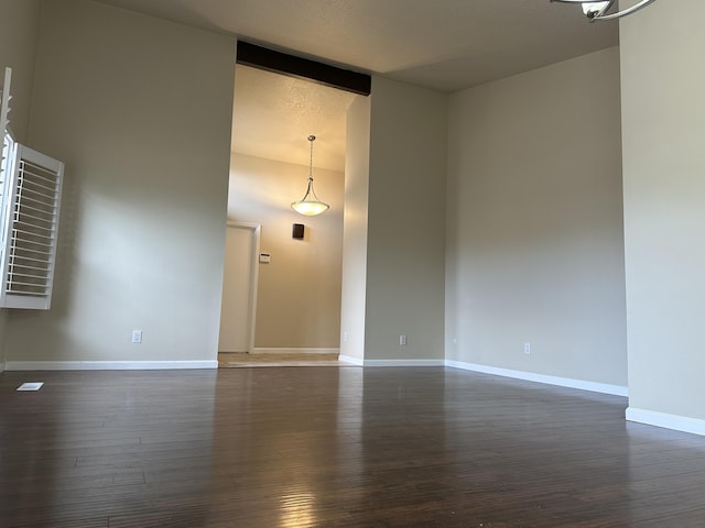 empty room featuring baseboards, dark wood-style flooring, and a towering ceiling