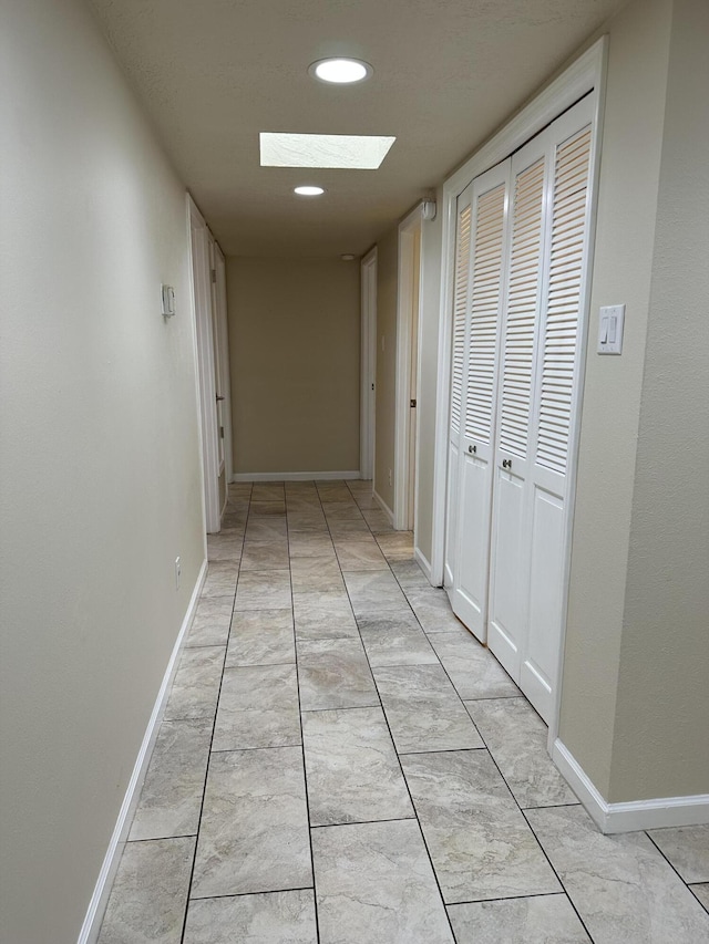 hall with recessed lighting, a skylight, and baseboards