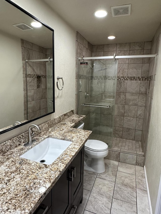 bathroom with visible vents, a shower stall, toilet, and vanity