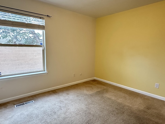 carpeted empty room featuring visible vents and baseboards