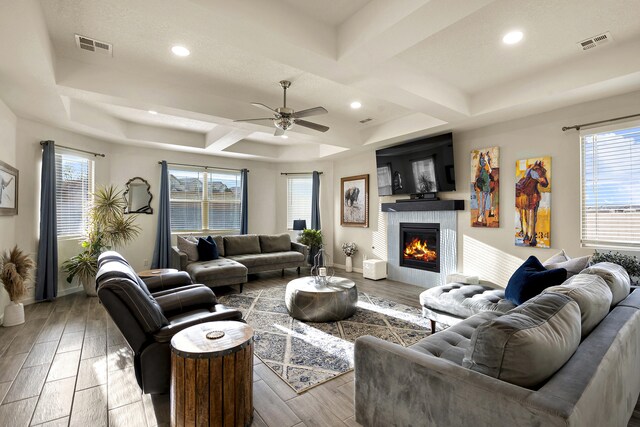 living room with light hardwood / wood-style floors, coffered ceiling, ceiling fan, and a healthy amount of sunlight