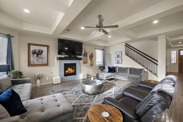 living room with ceiling fan, coffered ceiling, and a raised ceiling