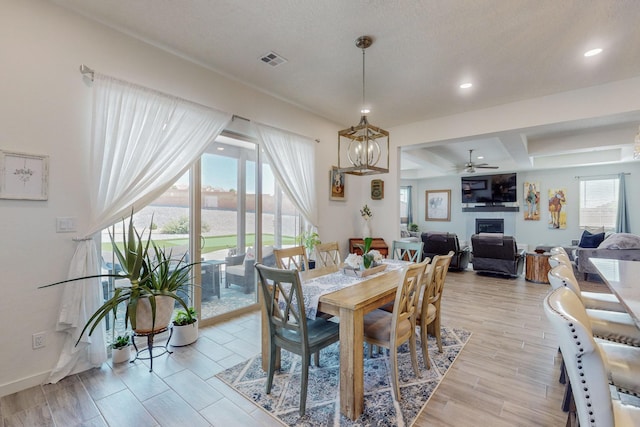 dining area with ceiling fan with notable chandelier and a fireplace