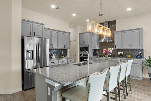 kitchen with ceiling fan, a center island with sink, sink, a kitchen breakfast bar, and stainless steel appliances